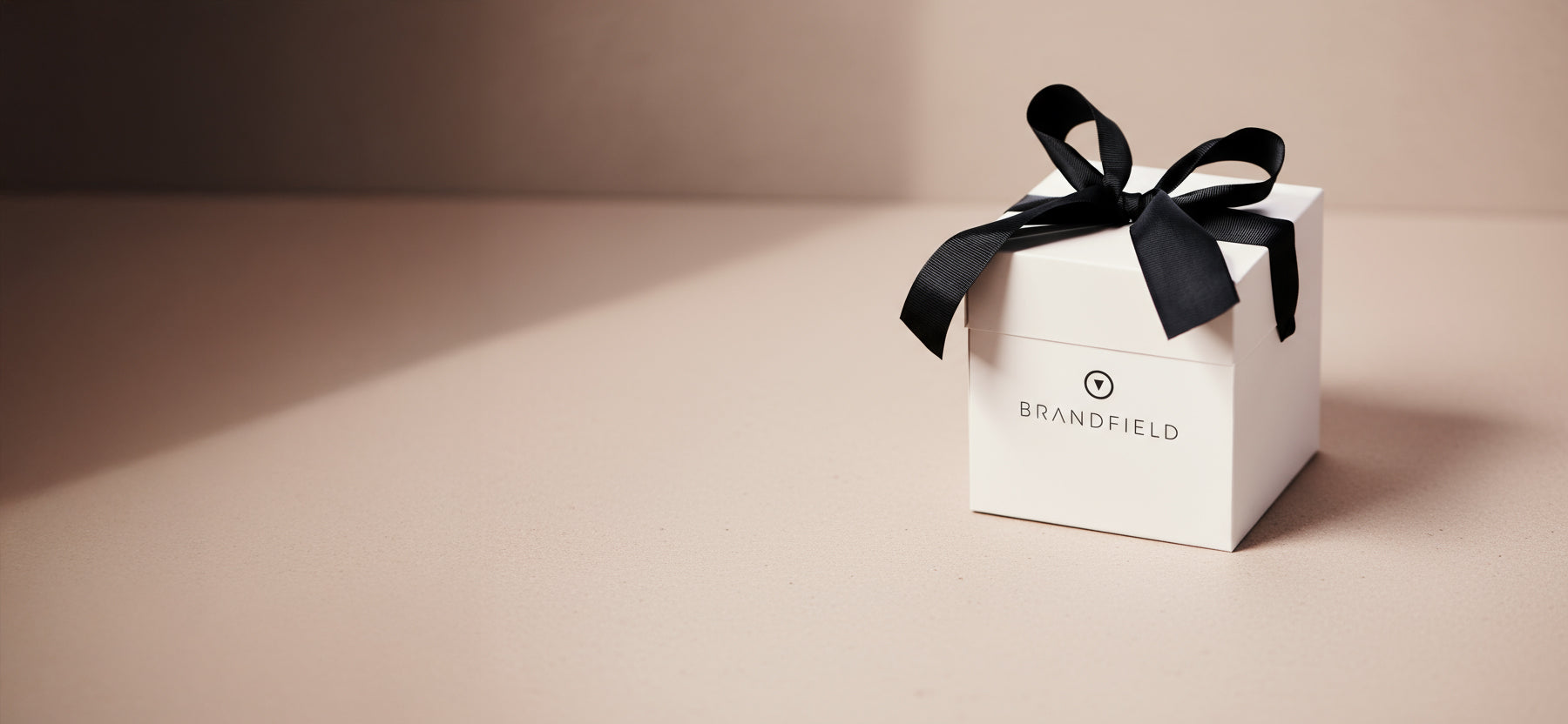 White gift box with a black ribbon on a beige background